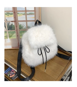 Detailed view of white faux fur backpack featuring black drawstrings and soft fluffy texture