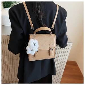 Detail of khaki quilted backpack with vintage buckle and cute plush puppy charm