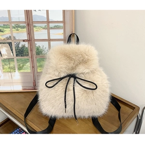 Close-up of soft beige plush backpack featuring black drawstring bow and fabric straps