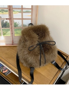 Detailed view of the brown plush backpack featuring a decorative black bow and soft texture
