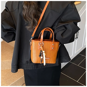 Détail du sac seau tressé orange-marron avec pendentif en perles et fine bandoulière