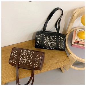 Close-up of black and brown pillow bags with silver rivets on a wooden bench