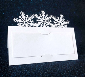 Macro shot of white snowflake laser-cut place cards on a blue shimmering background