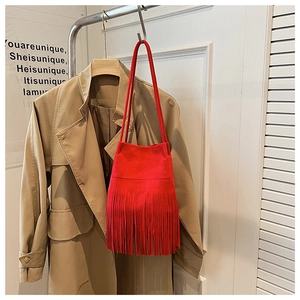 Detailed close-up of a red suede tassel shoulder bag styled with a khaki trench coat