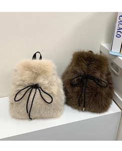 Detail of plush faux fur backpacks with black drawstring bows on white display steps
