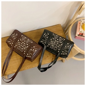 Detail of studded leather shoulder bags in dark brown and black on a wooden bench