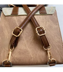 Detail view of adjustable dark brown faux leather straps and gold metal buckles on a tan bag