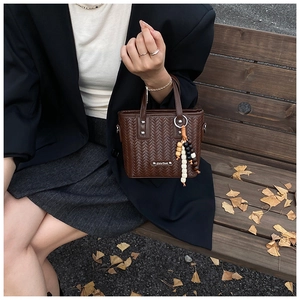 Détail du sac à main tissé marron foncé avec pendentif en perles de bois