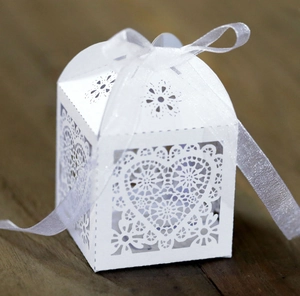 Detail einer weißen lasergeschnittenen Hochzeitsbox mit Herzmuster und Seidenschleife