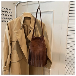 Detailed view of dark brown suede bucket bag with long fringe and slim shoulder strap
