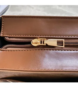 Detailed close-up of smooth gold zipper and stitching on brown leather handbag