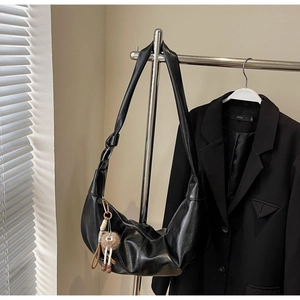 Close-up of black hobo bag in polished leather with cute plush ball pendant detail
