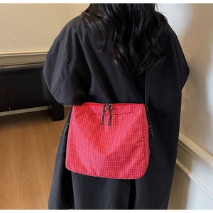 Detail of red checkered canvas tote bag with black zipper and adjustable buckle strap