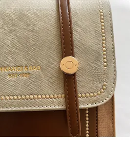 Close-up of cross-grain leather detail with star stitching and golden logo on handbag