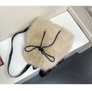 Detailed close-up of soft beige faux fur texture with a stylish black rope bow on the bag