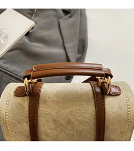Detail view of reinforced leather handles and golden metal D-rings on canvas backpack