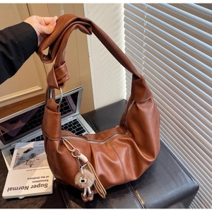 Detail of brown pebbled leather crescent bag with knotted strap and silver metal ring