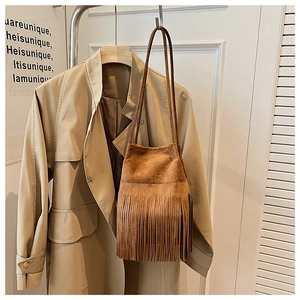 Detailed close-up of brown suede tassel shoulder bag hanging on a khaki coat