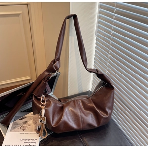Detail view of brown textured PU leather hobo bag with knotted strap and tassel charm