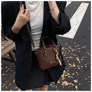 Détail d'un mini sac cabas marron foncé tressé avec perles sur tenue chic urbaine