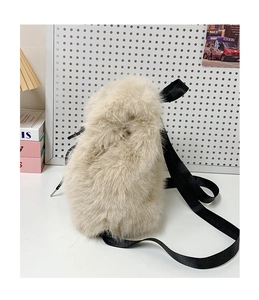 Close-up of plush faux fur backpack in beige with black nylon straps on a white desk