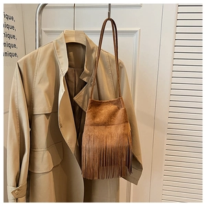 Detailed close-up of brown suede shoulder bag with bohemian fringe and long strap