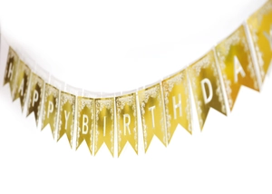Détail du bord en dentelle laser sur la bannière dorée Happy Birthday à fanions