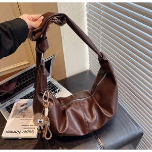 Detailed view of dark brown hobo bag with litchi texture and decorative knot shoulder strap