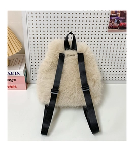 Detail of the light beige plush backpack showing soft faux fur texture and black nylon straps