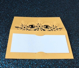 Detail showing laser-cut snowflake design on cream place card with sparkling background