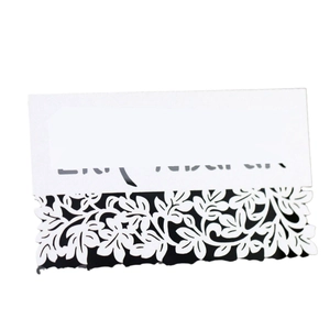 White laser-cut wedding place card with intricate floral lace pattern and black lining