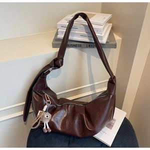 Detailed view of brown ruched crescent bag with silver zipper and plush bear charm