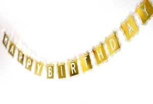 Détail d'une bannière de Joyeux Anniversaire dorée avec dentelle et lettres blanches