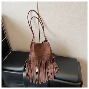 Close-up of brown suede bucket bag featuring long bohemian tassels and shoulder straps
