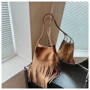 Detailed view of brown suede bucket bag with long fringe tassels and thin double straps