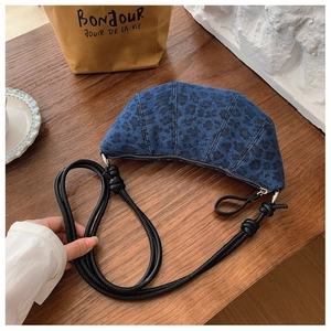 Dettaglio della borsa a tracolla croissant in denim leopardato blu con tracolla in pelle