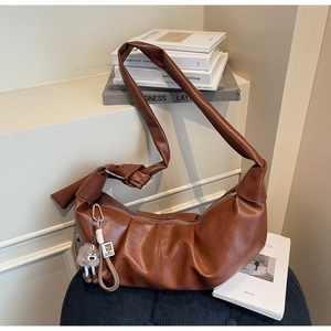 Detail of dark brown pleated hobo bag in PU leather with plush eye-shaped pendant