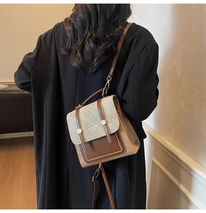Detail of grey suede and brown leather backpack with buckle straps worn by a model