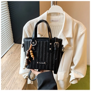 Détail du sac seau noir tressé avec clous argentés et breloque rétro en perles de bois