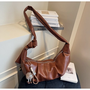 Detailed shot of brown pleated shoulder bag with knotted strap and plush charm