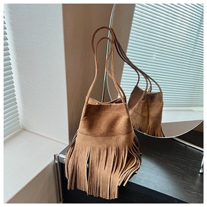 Detailed view of a brown suede bucket bag featuring long fringe tassels and thin straps