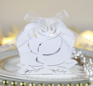 Laser-cut white paper rose wedding favor box with ribbon on decorative plate