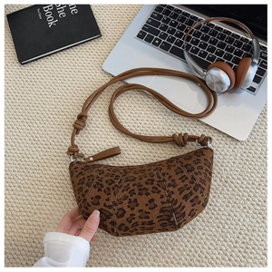 Dettaglio della borsa a mezzaluna leopardata con tracolla in pelle su maglia bianca