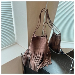 Detailed close-up of brown suede bucket bag with long tassels and drawstring closure