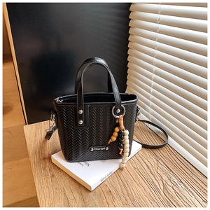 Détail d'un sac à main noir tressé avec perles en bois et ombre de fenêtre élégante