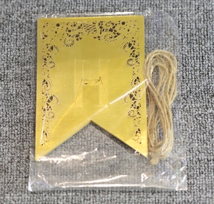 Détail de carte dorée découpée au laser avec lettre H pour bannière de fête DIY