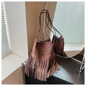 Detailed view of deep brown suede bucket bag featuring long fringe and thin shoulder strap