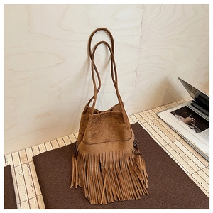 Close-up of brown suede bucket bag with long tassels and delicate thin double straps