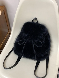 Chic black faux fur backpack featuring soft plush texture and elegant bow drawstring detail