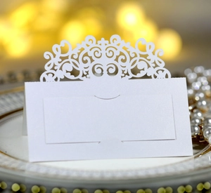 Détail du marque-place blanc découpé au laser avec arabesques sur une assiette dorée